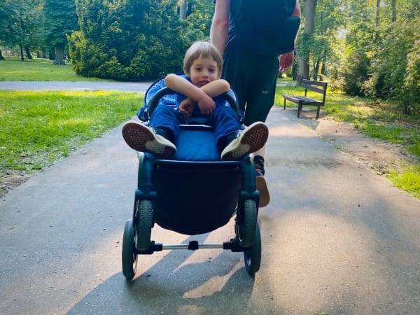 Petite&Mars Royal stroller on the rear wheels, happy boy inside